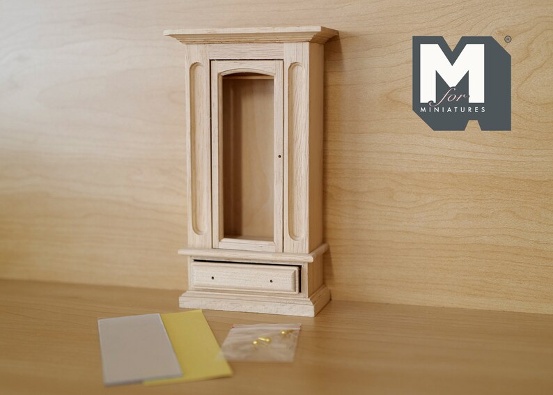 May include: A wooden dollhouse cabinet with a glass door and a drawer. The cabinet is unfinished and ready to be painted or stained.
