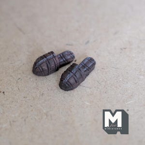 Op de afbeelding: Een paar bruine geweven mini-pantoffels. De pantoffels hebben een geruit patroon en zijn gemaakt van een getextureerd materiaal.