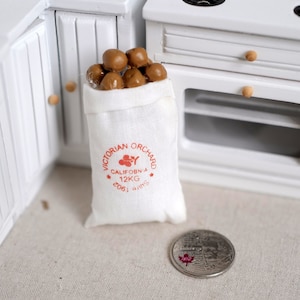 May include: A white hessian sack filled with brown potatoes. The sack has a red label that reads "Victorian Orchard, California, 12KG, 2061", with a small red flower graphic.