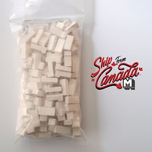 Op de afbeelding: Een doorzichtige plastic zak gevuld met witte rechthoekige bouwstenen. De zak is gelabeld met "Verzending vanuit Canada".