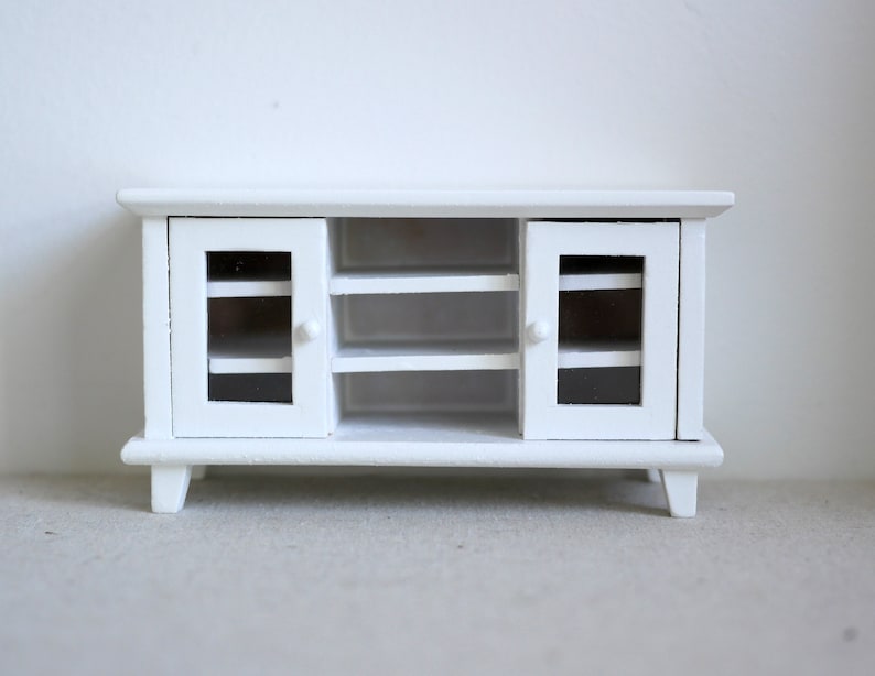 Pode incluir: Um arm&aacute;rio de madeira branco com duas portas de vidro e duas prateleiras. O arm&aacute;rio tem um design simples e &eacute; perfeito para guardar pequenos objetos.