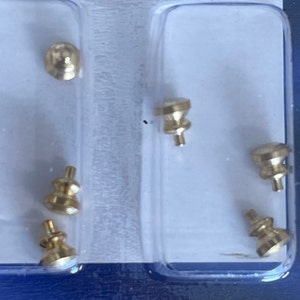 May include: A pack of six gold-coloured metal drawer pulls. The pulls are in a clear plastic pack with a blue background.