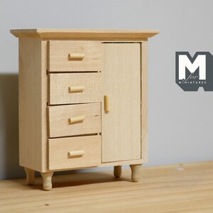 May include: A wooden miniature dresser with four drawers and a cabinet door. The dresser has a light wood finish and small wooden legs.