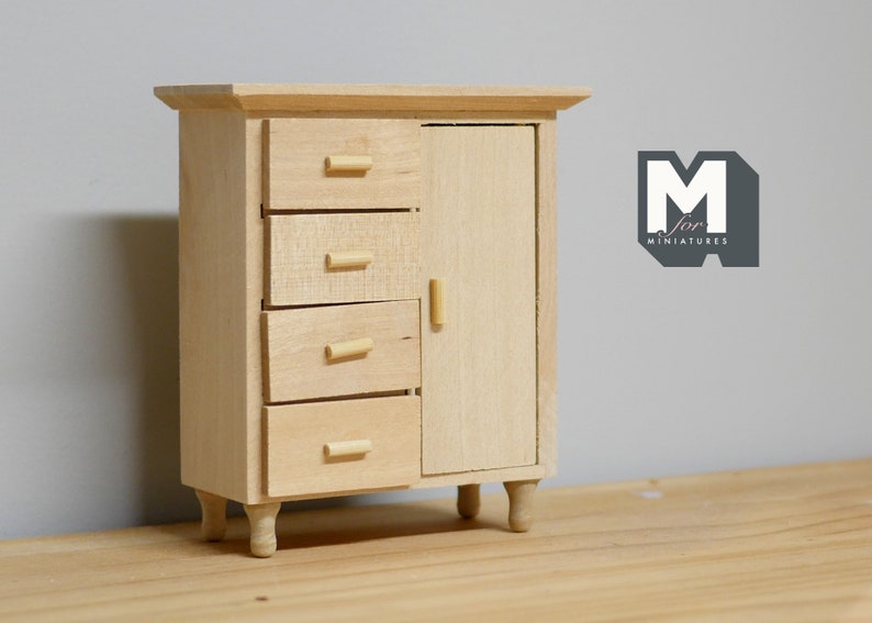 May include: A wooden miniature dresser with four drawers and a cabinet door. The dresser has a light wood finish and small wooden legs.