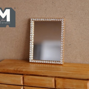 May include: A miniature rectangular mirror with a gold-colored frame encrusted with small, clear rhinestones. The mirror is set on a wooden dresser. The logo "M for MINIATURES" is in the upper left corner.