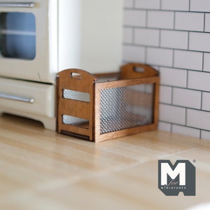 Könnte beinhalten: Ein kleiner Holzkasten mit einer Vorderseite aus Drahtgeflecht. Der Kasten ist braun und hat eine natürliche Holzoptik. Er steht auf einer Holzoberfläche.