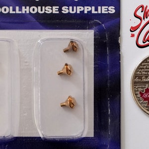 May include: A pack of five gold-coloured metal dollhouse door knobs. The knobs are packaged in two clear plastic blister packs. A Canadian 25-cent coin is included for size reference.