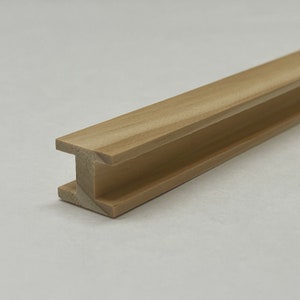 May include: A wooden I-beam model, a miniature version of a structural support beam, made of light brown wood.