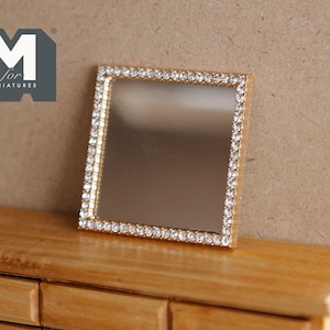 May include: A miniature square mirror with a gold-colored frame encrusted with small, clear rhinestones. The mirror is displayed on a wooden surface. The logo "M for MINIATURES" is in the upper left corner.