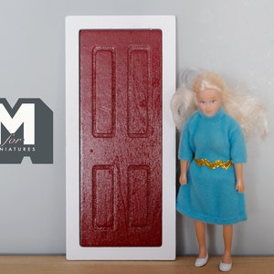 May include: A red wooden dollhouse door with white trim. The door has four raised panels and is about the size of a doll.