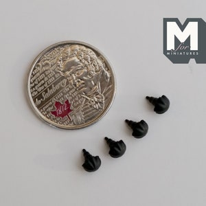 May include: Four black plastic furniture feet with a rounded top. The feet are about the size of a Canadian quarter.