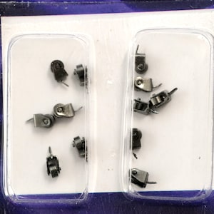 May include: A close-up of two clear plastic containers filled with small, silver-colored metal rollers. The rollers are arranged in a random pattern and appear to be for a craft or hobby project.