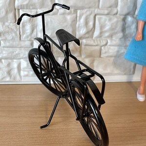 May include: A black metal bicycle model with a kickstand. The bicycle has a curved handlebar, a seat, and two wheels.