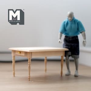 May include: A miniature wooden table with a single drawer and turned legs. The table is made of light wood and has a gold knob on the drawer. The table is approximately 38 cm long and 25 cm wide.