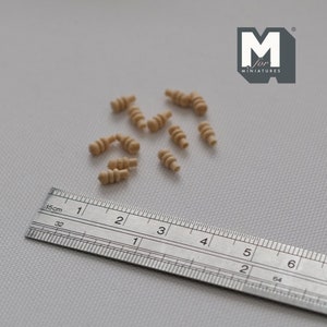 Könnte beinhalten: Ein Lineal mit einer Länge von 15 cm und einer Gruppe von 10 kleinen Holzstiften mit einem Spiralmuster. Die Stifte sind etwa 1,2 cm lang.