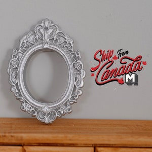 May include: Silver ornate oval picture frame with intricate floral details. The frame is approximately 7.6 cm in diameter.