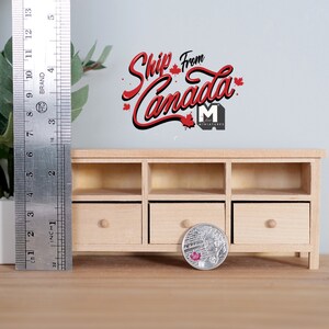 May include: A miniature wooden cabinet with three drawers and open shelves. A metal ruler shows the cabinet is approximately 4 inches tall. A coin and a small potted plant are in the foreground. The text "Ship From Canada" is above the cabinet.