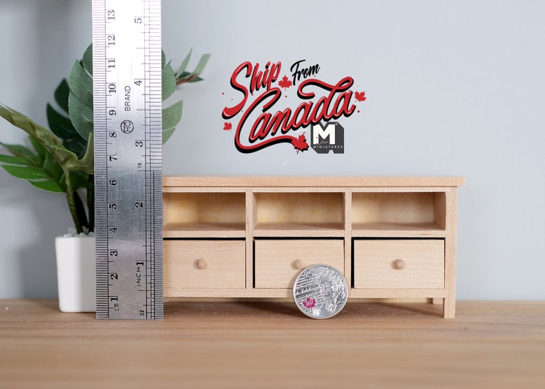 May include: A miniature wooden cabinet with three drawers and open shelves. A metal ruler shows the cabinet is approximately 4 inches tall. A coin and a small potted plant are in the foreground. The text "Ship From Canada" is above the cabinet.