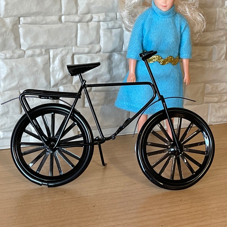 May include: A black metal bicycle with a basket and a rack. The bicycle has a black seat and black tires.