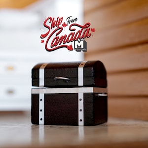 May include: A small black wooden treasure chest with silver accents and a metal handle. The chest is closed and sitting on a white surface. The text "Ship from Canada" is written in red above the chest.