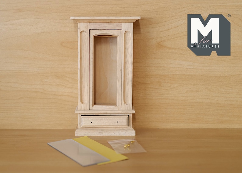 May include: A wooden dollhouse cabinet with a glass door and a drawer. The cabinet is unfinished and ready to be painted or stained. It is made by M for Miniatures.