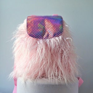 May include: A pink faux fur backpack with an iridescent mermaid scale flap.