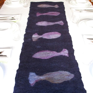May include: A dark blue table runner with a repeating pattern of five purple and gray fish silhouettes.