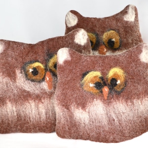 May include: Three brown felt owl-shaped pillows with white fur and embroidered eyes.