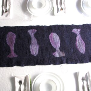 May include: A dark purple felt table runner with a repeating pattern of stylized fish silhouettes. The fish are a light purple color.
