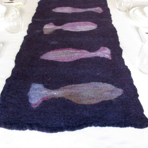 May include: A dark blue felt table runner with a design of five light purple and gray fish.