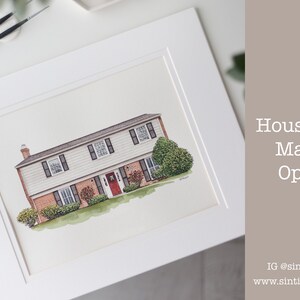 Op de afbeelding: Waterverfschilderij van een huis met twee verdiepingen met een bakstenen gevel, zwarte luiken en een rode voordeur, ingelijst in een witte lijst. Het kunstwerk is getiteld "House Only Matted Option".