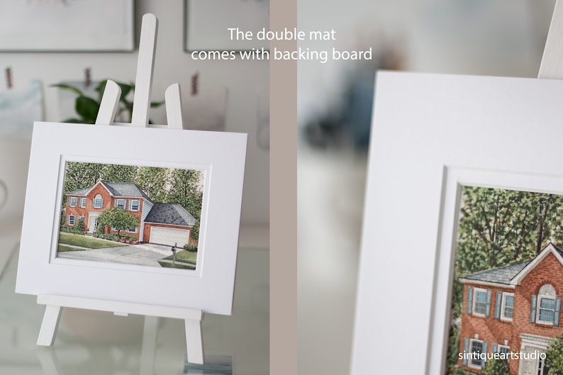 Op de afbeelding: Een ingelijste aquarel van een huis met een rode bakstenen buitenkant, tentoongesteld op een witte ezel. De dubbele passe-partout wordt geleverd met een achterbord. De schildering staat tegen een achtergrond van groene bomen en een blauwe lucht.