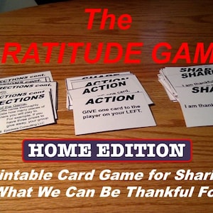 May include: A card game titled "The Gratitude Game: Home Edition" with instructions and action cards. The game encourages sharing what one is thankful for. The cards are white with black text, and the title is in red.