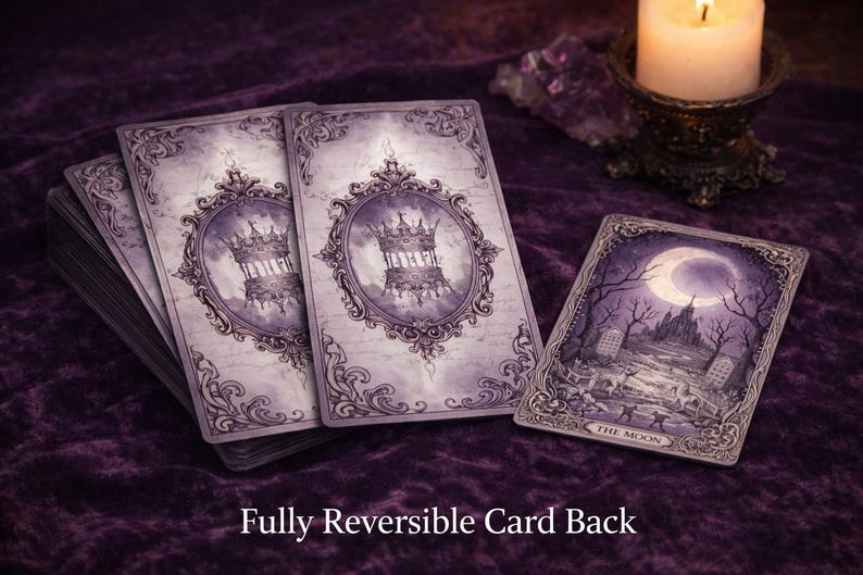 May include: A deck of rectangular tarot cards with a purple and white colour palette. The card backs feature an ornate frame surrounding a crown illustration. One card is face up, displaying a moonlit landscape with the text The Moon at the bottom.