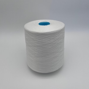 May include: A large spool of white yarn with a blue center. The yarn is tightly wound, creating a cylindrical shape. The image is taken against a plain white background, highlighting the texture and color of the yarn.