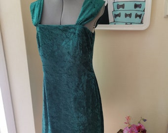 May include: A teal green velvet dress with a square neckline and straps. The dress is fitted and has a short length.