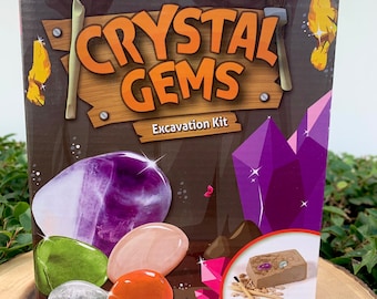 May include: A Crystal Gems Excavation Kit box with colorful gemstones and tools. The box features the text "Crystal Gems Excavation Kit" and "6+". The kit includes a variety of colorful gemstones and excavation tools.