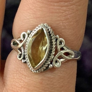 May include: A silver ring with a marquise-shaped, light brown gemstone set in a detailed silver setting.