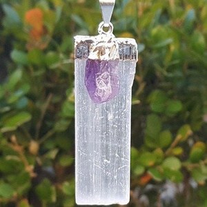 May include: A silver necklace with a white selenite crystal pendant and a small amethyst crystal charm.