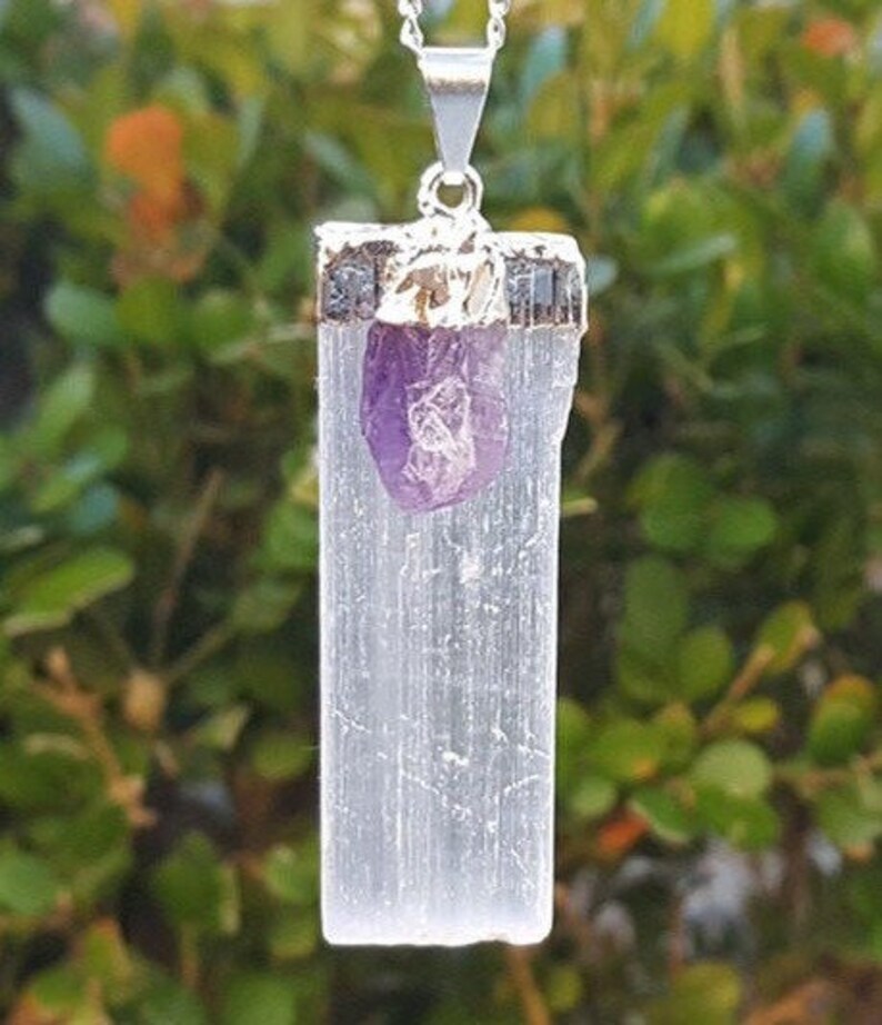 May include: A silver necklace with a white selenite crystal pendant and a small amethyst crystal charm.