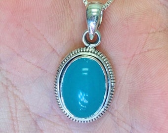 May include: A silver pendant necklace with a light blue oval gemstone set in a silver bezel.
