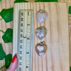 Puede incluir: Tres colgantes de coraz&oacute;n de &aacute;gata rosa con un aro de plata, medidos con una regla en pulgadas. Los colgantes miden aproximadamente 1 pulgada.