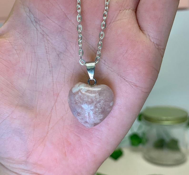 Puede incluir: Un collar de cadena de plata con un colgante en forma de coraz&oacute;n hecho de &aacute;gata rosa y blanca.