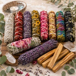Könnte beinhalten: Eine Sammlung zylindrischer Räucherbündel, die mit weißer Schnur umwickelt sind und verschiedene getrocknete Pflanzen enthalten, darunter rote Rosenblätter, violetter Lavendel, gelbe Sonnenblumen, bunte Wildblumen sowie drei Palo-Santo-Holzstäbe.