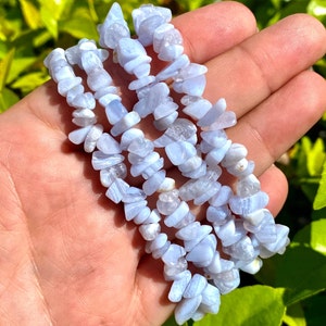 May include: Three blue lace agate chip bracelets stacked on top of each other. The bracelets are made of small, irregular shaped chips of blue lace agate.