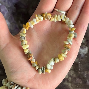 May include: A bracelet made of small, irregular, chipped, and polished stones in shades of white, brown, and yellow.