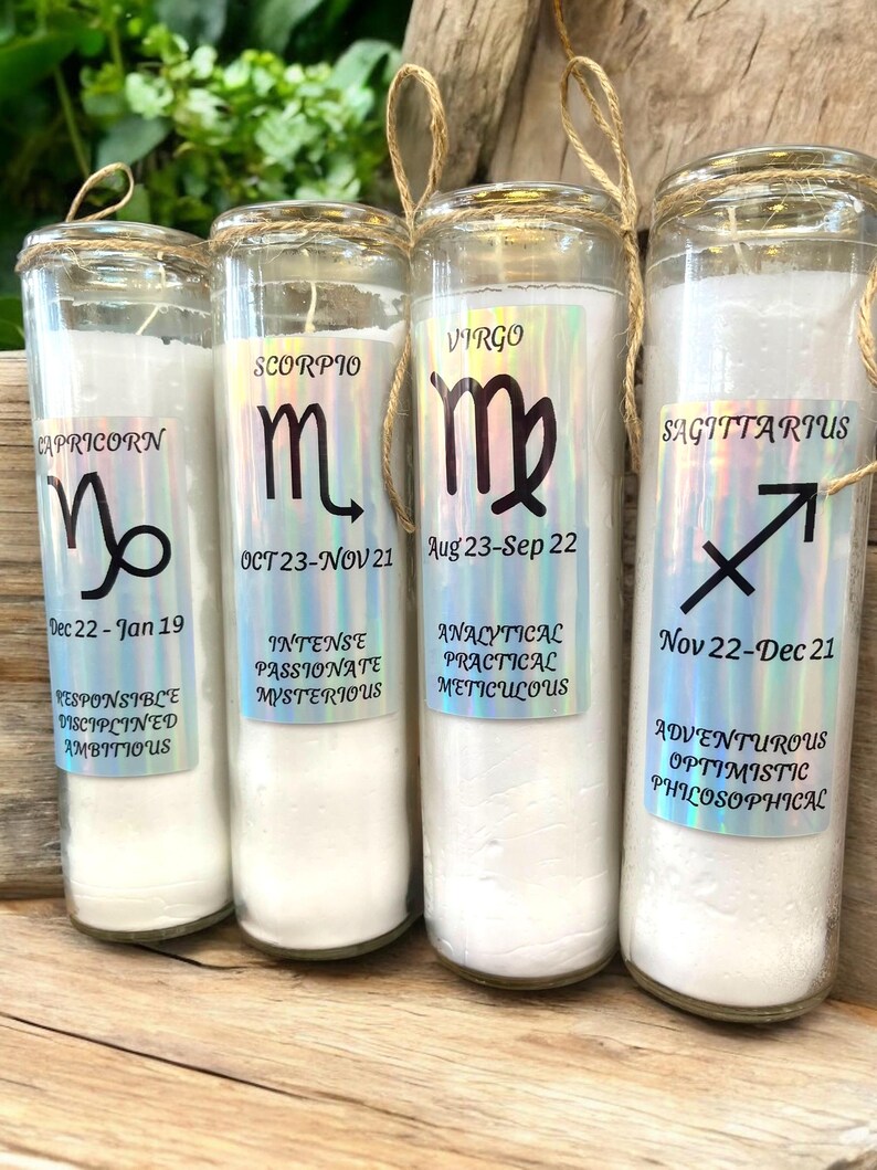 Puede incluir: Cuatro tarros de velas de vidrio con velas blancas y signos del zod&iacute;aco y fechas impresos en el frente. Los signos son Capricornio, Escorpio, Virgo y Sagitario.