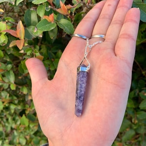 May include: A silver chain with a purple crystal pendant. The crystal is a point shape and has a silver cap at the top.
