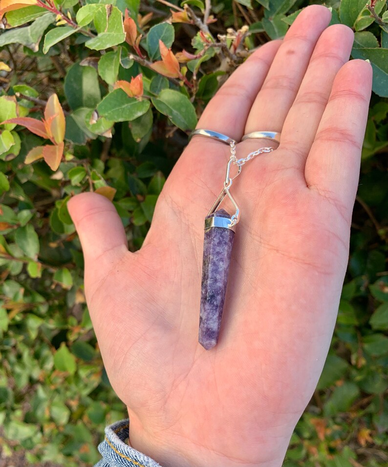 May include: A silver chain with a purple crystal pendant. The crystal is a point shape and has a silver cap at the top.