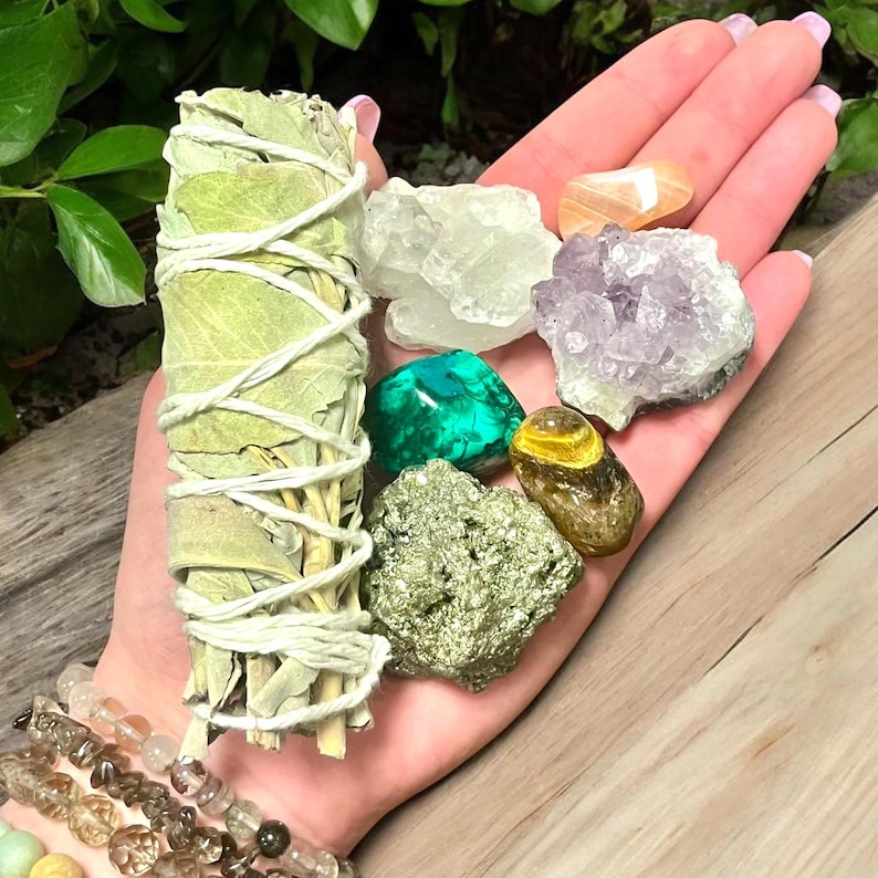 Peut inclure: Une collection de cristaux et un paquet de b&acirc;tonnets de sauge pour la purification. Les cristaux comprennent l'am&eacute;thyste, le quartz clair, la malachite, l'&oelig;il de tigre et la pyrite.